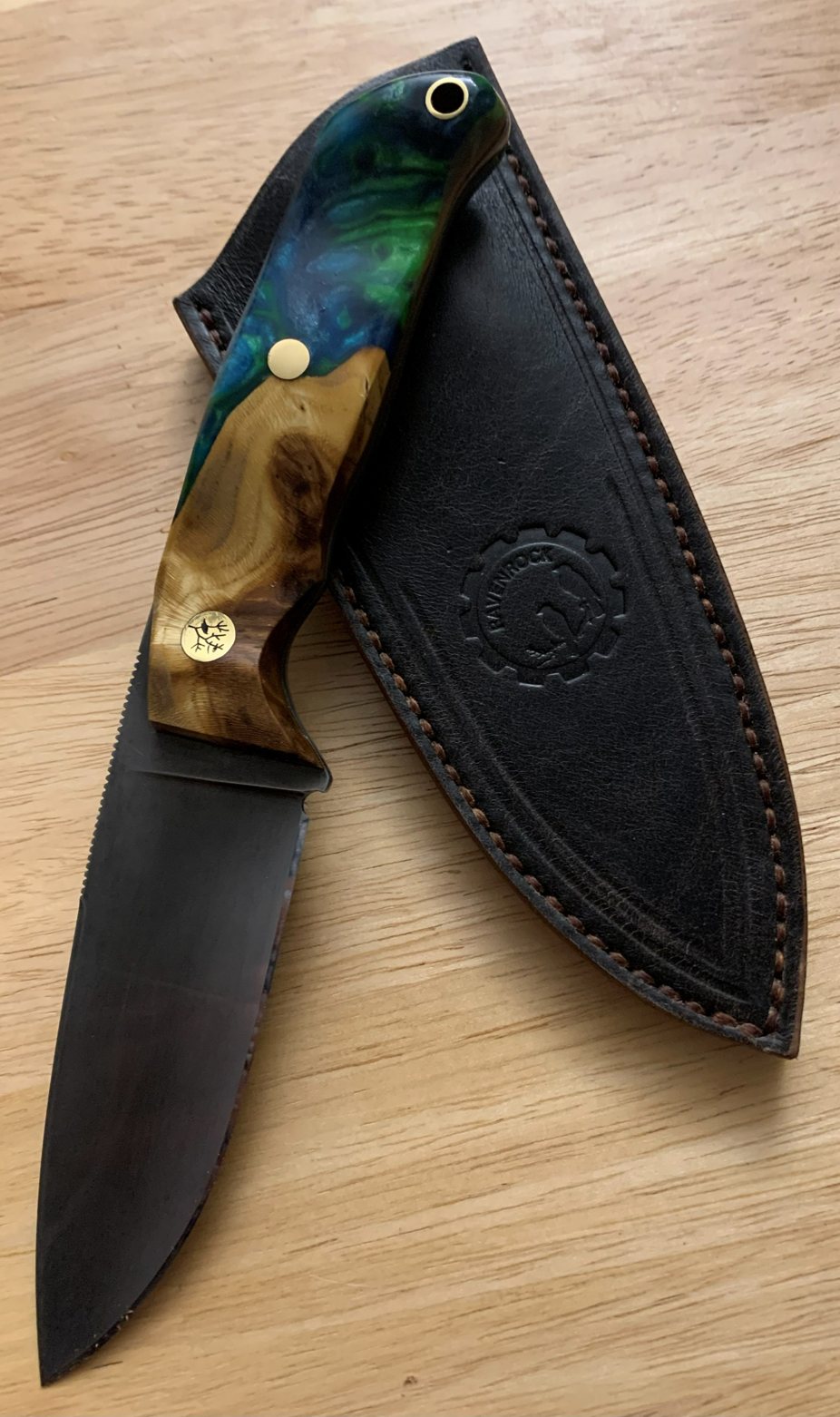 RRK-01-009 in full, an acid-etched dark blade with blue-green resin and burl handle, resting on its hand-stitched leather sheath
